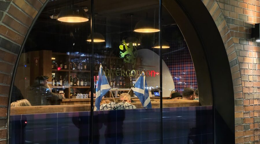 View through the front window of Invergordon Bar in Docklands, Melbourne, showing the warm interior and bar area.