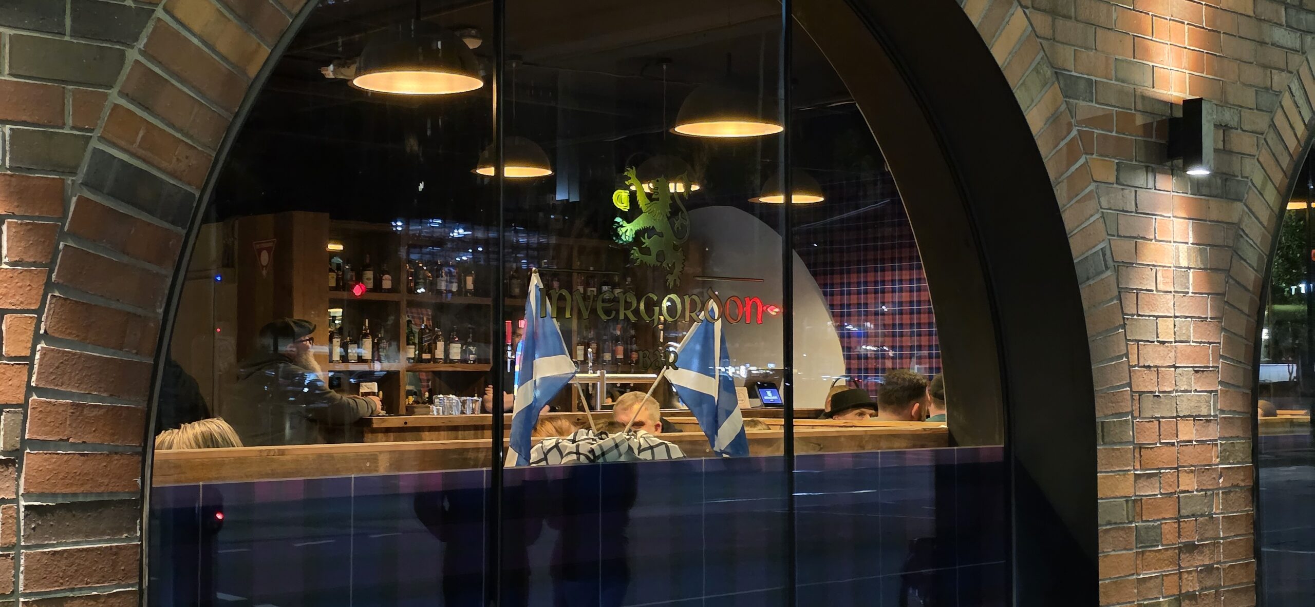 View through the front window of Invergordon Bar in Docklands, Melbourne, showing the warm interior and bar area.